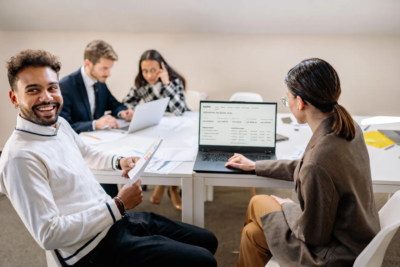 Ein Team im Büro mit Laptop und ausgedruckten Auswertungen